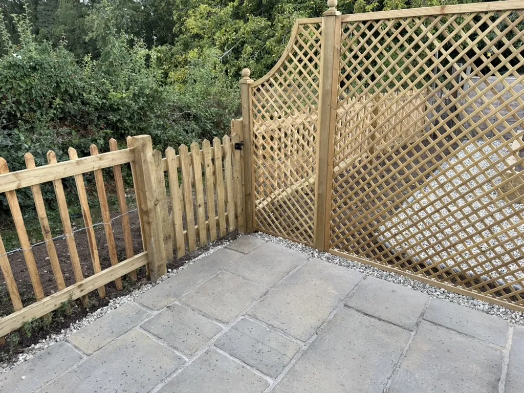 Cleft picket fencing and curved lattice trellis beside sawn stone paving